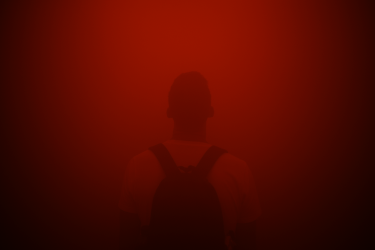 A silhouette of a person wearing a backpack standing in a dense, immersive red fog, part of Olafur Eliasson's art installation “Din Blinde Passager” (“Your Blind Passenger”). The vibrant red haze engulfs the entire scene, creating an otherworldly and disorienting atmosphere. The figure, with minimal visible details, appears to be enveloped in the fog, evoking themes of perception, isolation, and sensory experience. Captured on a Nikon D5300 digital camera. - A work by John Paglia