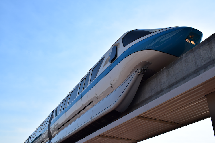 Monorail Blue glides smoothly along its elevated track under a clear blue sky at Walt Disney World, Orlando, Florida. The sleek and futuristic design of the monorail is highlighted against the minimalistic backdrop, showcasing its iconic transportation system within the resort. Captured on a Nikon D5300 digital camera. A Work by John Paglia.